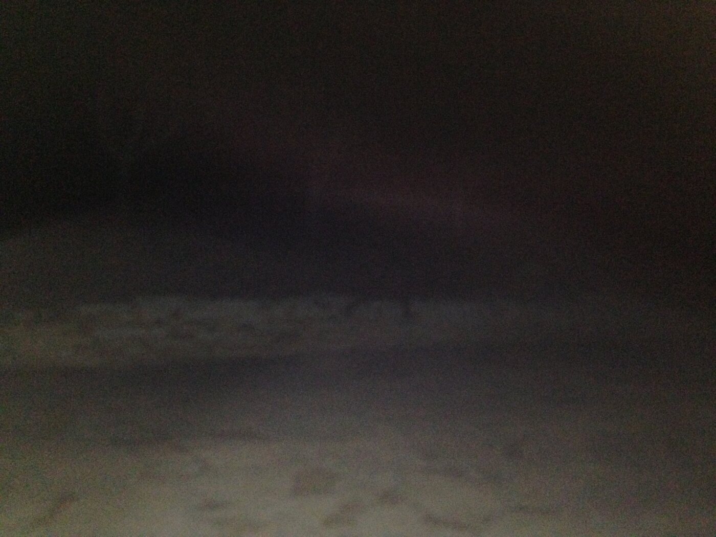 Foto noturna quase toda escura; o flash iluminou só o chão de pedra perto da câmera